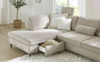 Elegantes Ecksofa in Beige mit integrierter Schublade als Stauraum. Das Sofa steht auf schwarzen Füßen im hellen Wohnzimmer und bietet hohen Sitzkomfort kombiniert mit praktischer Funktionalität für modernes Wohnen.